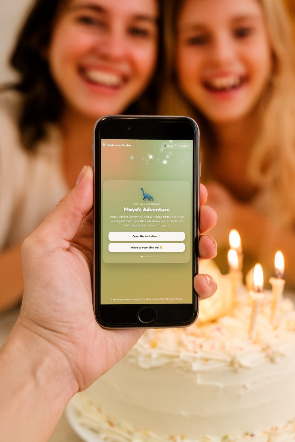A hand holding an iPhone showing a real Celebration Studios birthday invitation